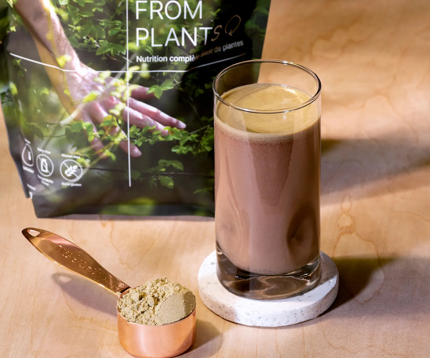 A glass of HEAL meal replacement, with the powder in a measuring spoon next to the glass, and the bag of HEAL in the background.